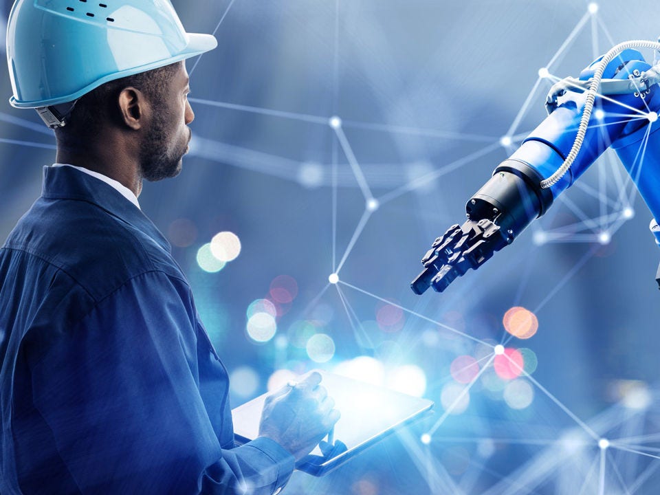 Black engineer in hard hat working with robotic arm