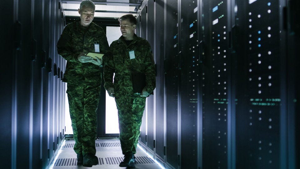 Duo in green camo military fatigues walk through data center
