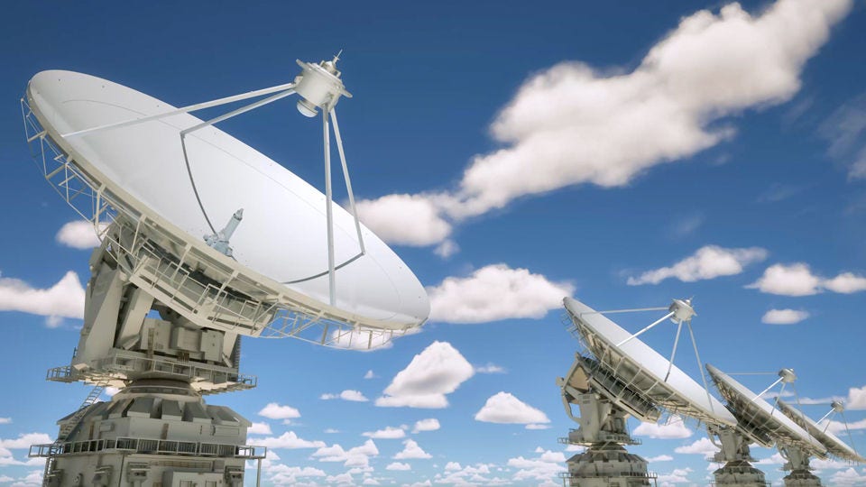 Series of satellite dishes in front of a cloudy blue sky