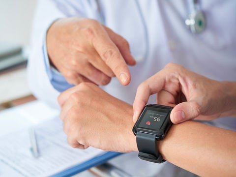 Patient wearing a sleek wristband or patch-style health monitor, paired with a smartphone app