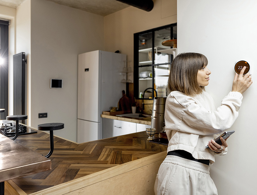 Woman controlling home temperature with electronic Woman controlling home temperature with electronic